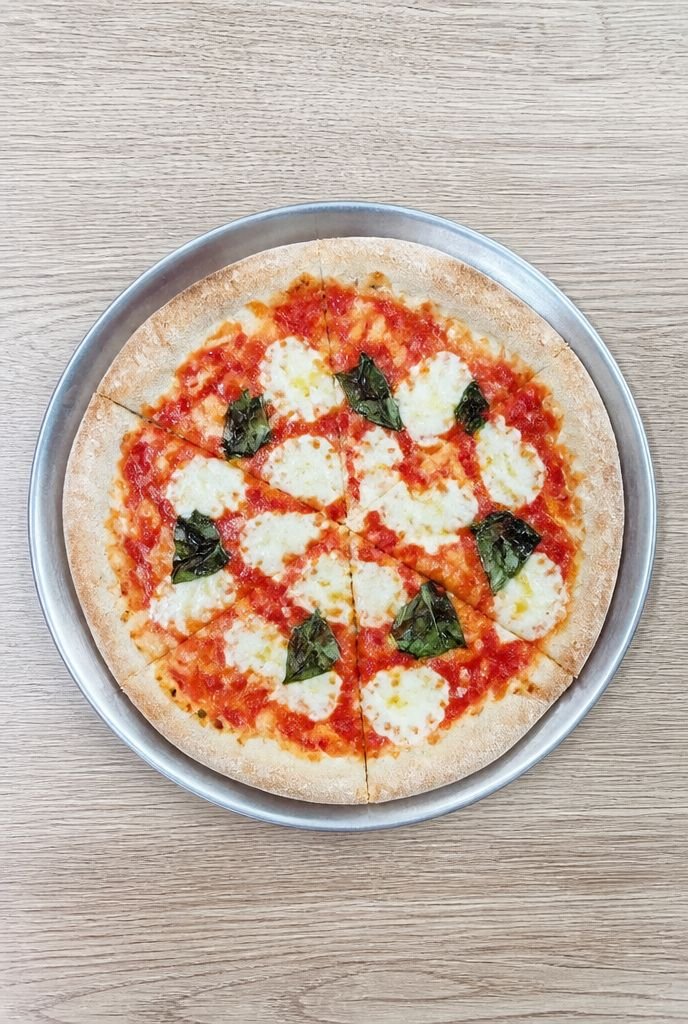 Flat, evenly lit phone photo of a pizza on a metal pan